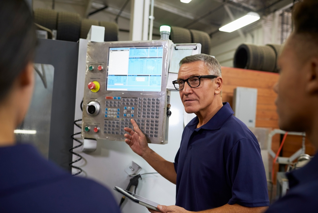 Man pointing to CNC machine during CNC machinist job