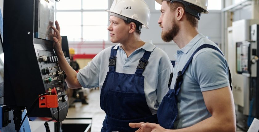 CNC Engineer working on CNC machine with coworker